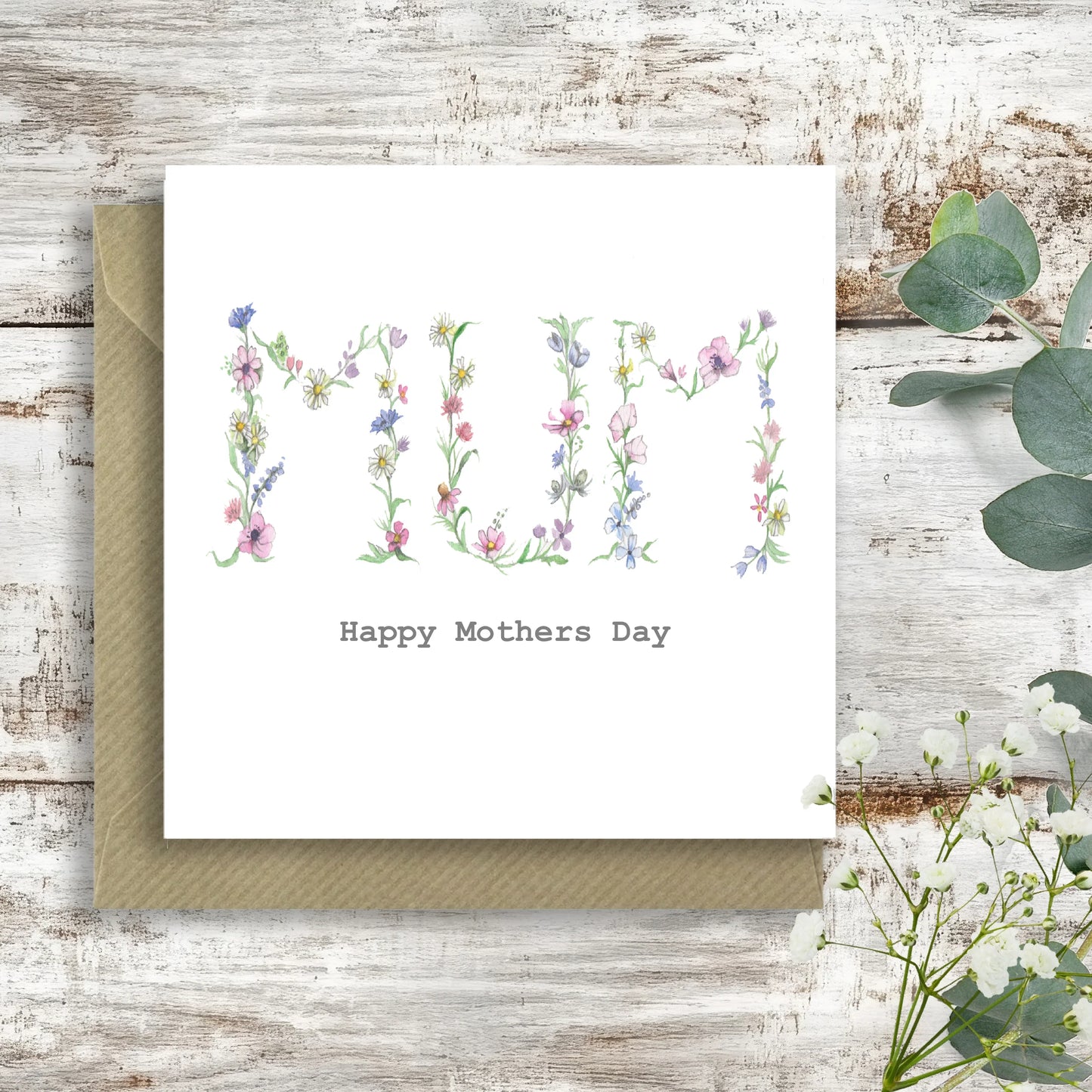 Crumble and Core floral 'Mum' Happy Mothers Day card on rustic wood with envelope and greenery
