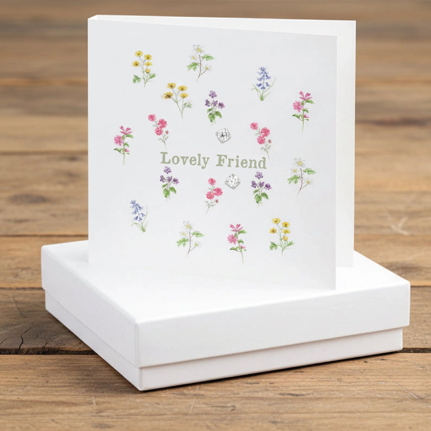 Lovely Friend greeting card with colorful floral illustrations on a white box, wood background