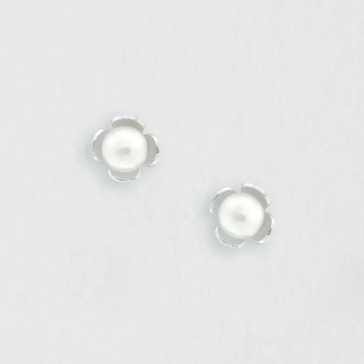 A pair of white pearl earrings with a flower-shaped design.